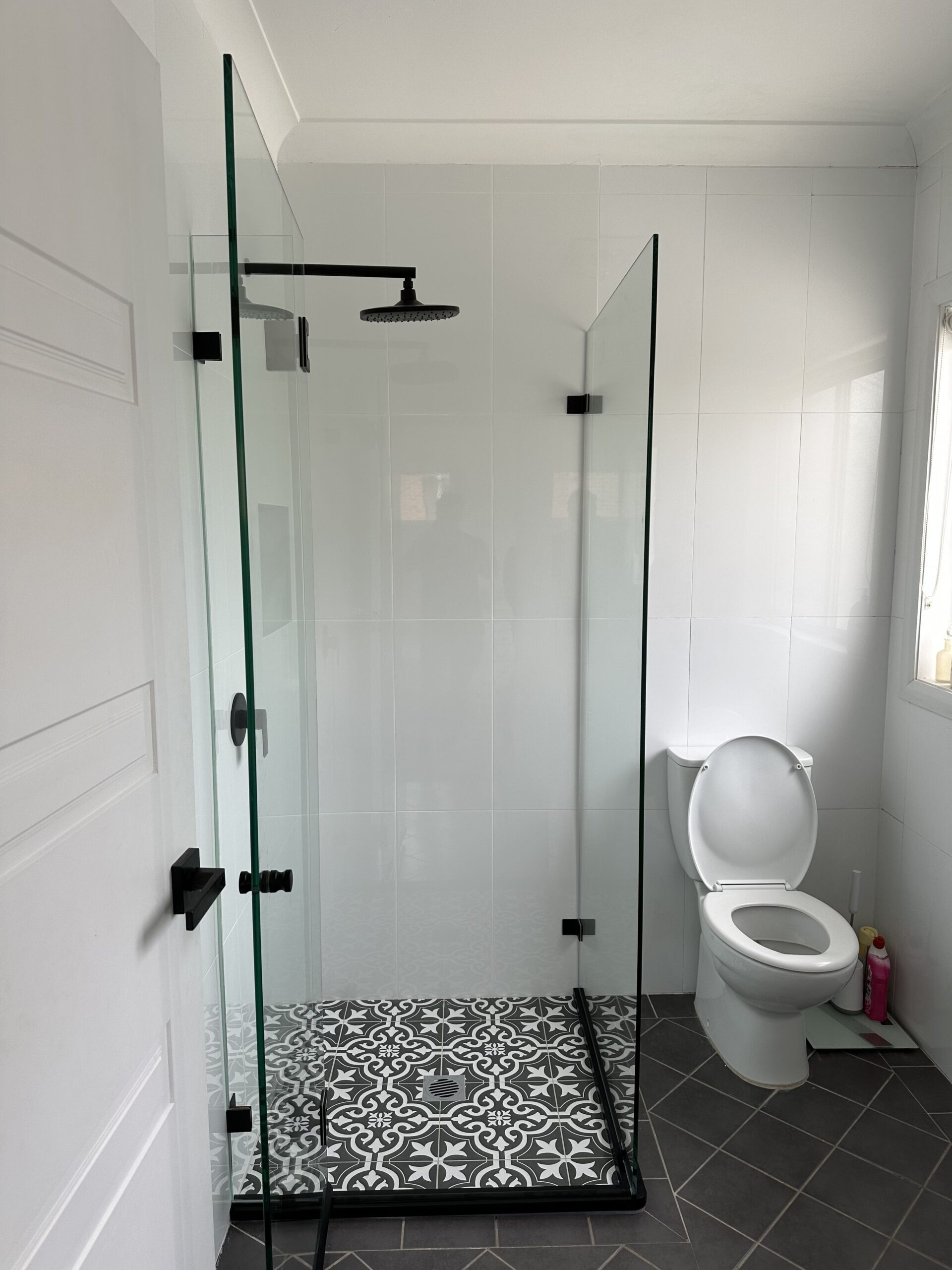 Completed shower repair in Sydney, new floor tiles, wall tiles and glass shower doors completed with new black hardware.