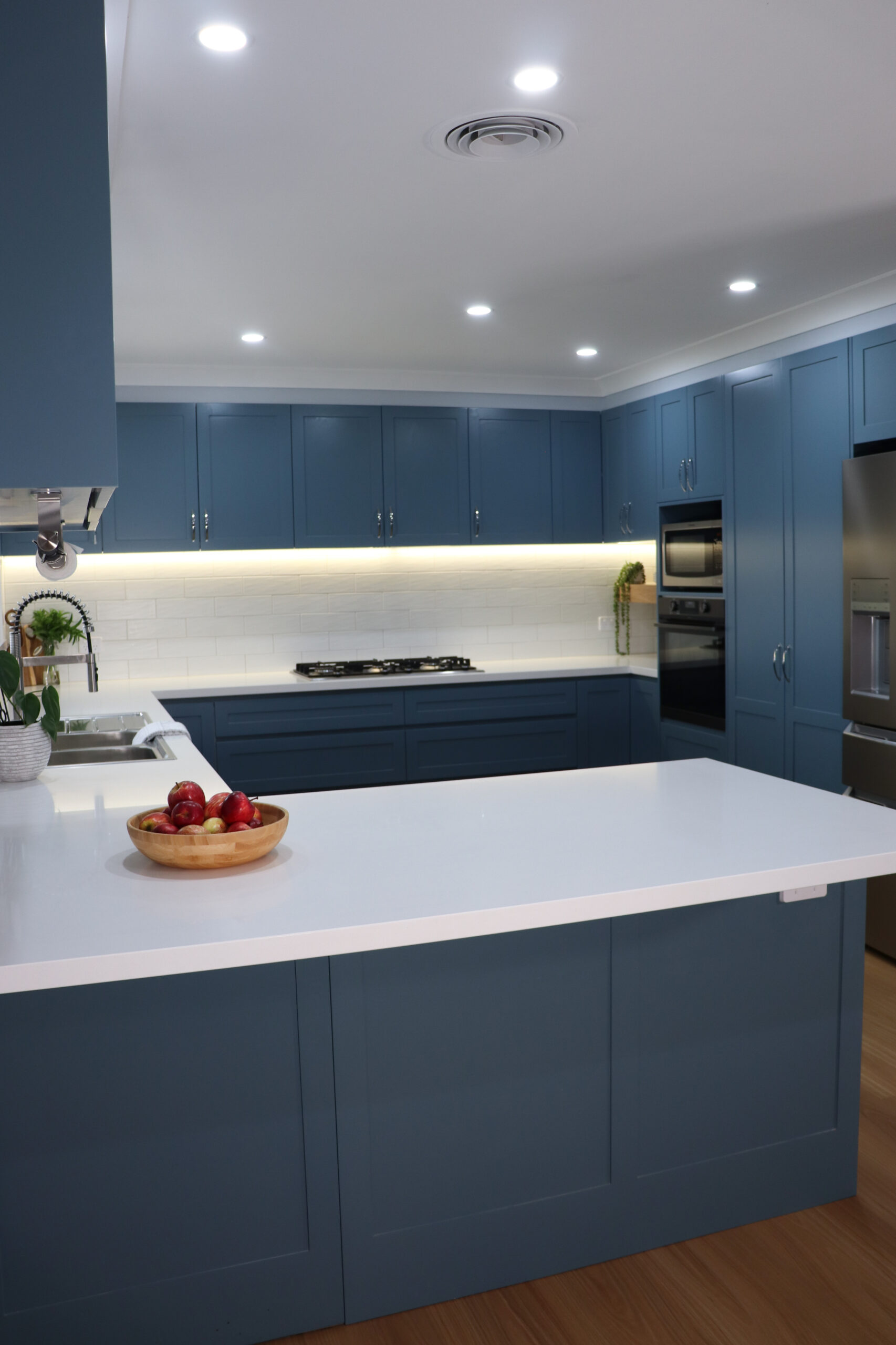 Portrait image of new, blue, modern family kitchen renovation with breakfast bar.