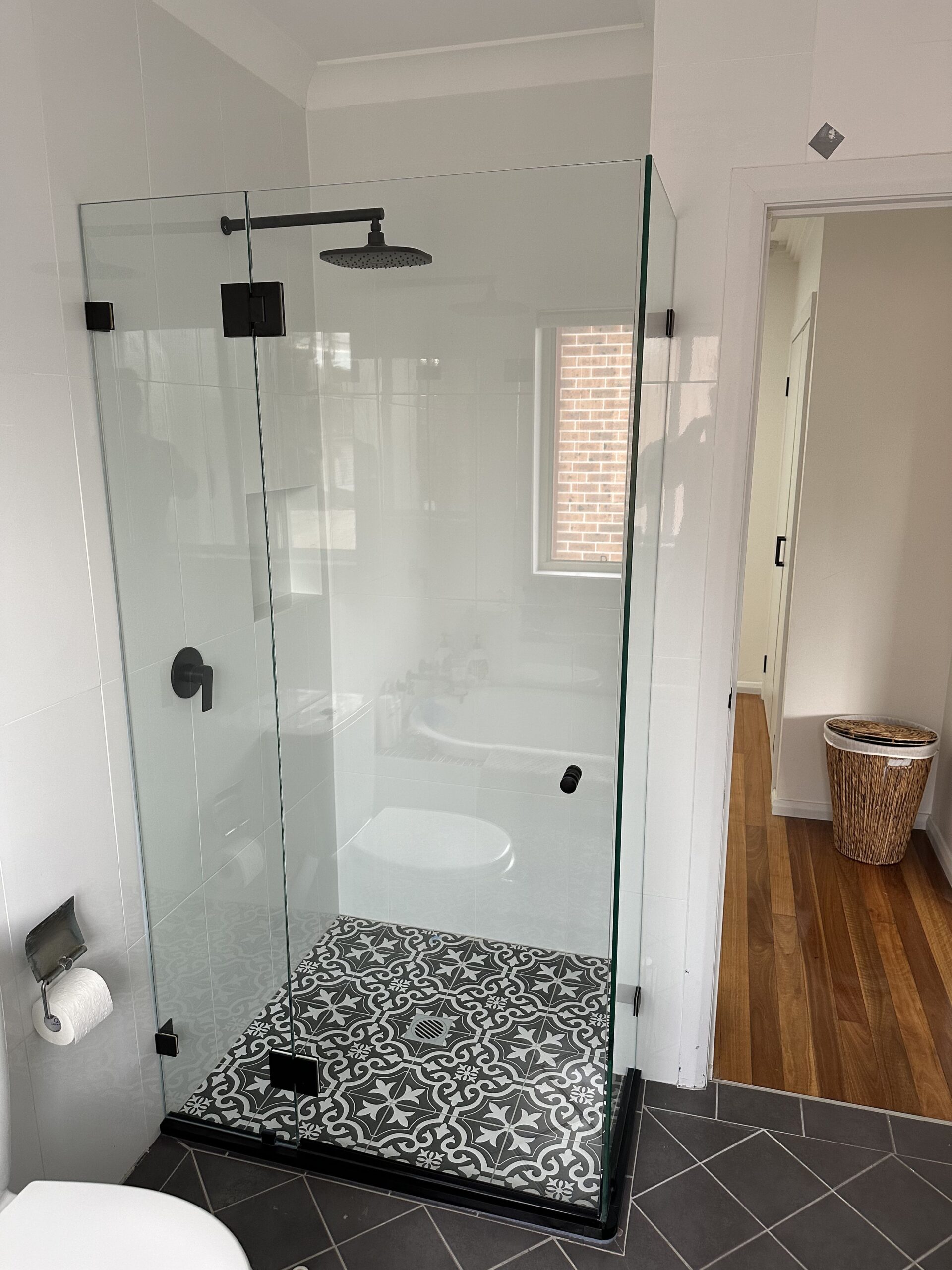 Final finished shower repair with brand new checked tiled floor and glass surround.