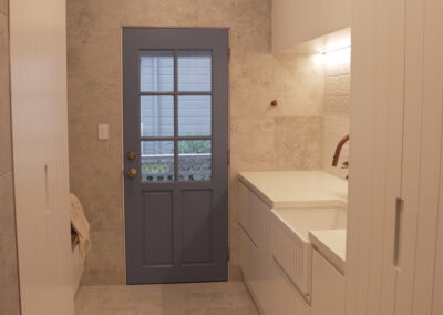 Rustic mudroom entryway with embedded sink on the right, cabinets and blue farmhouse door.