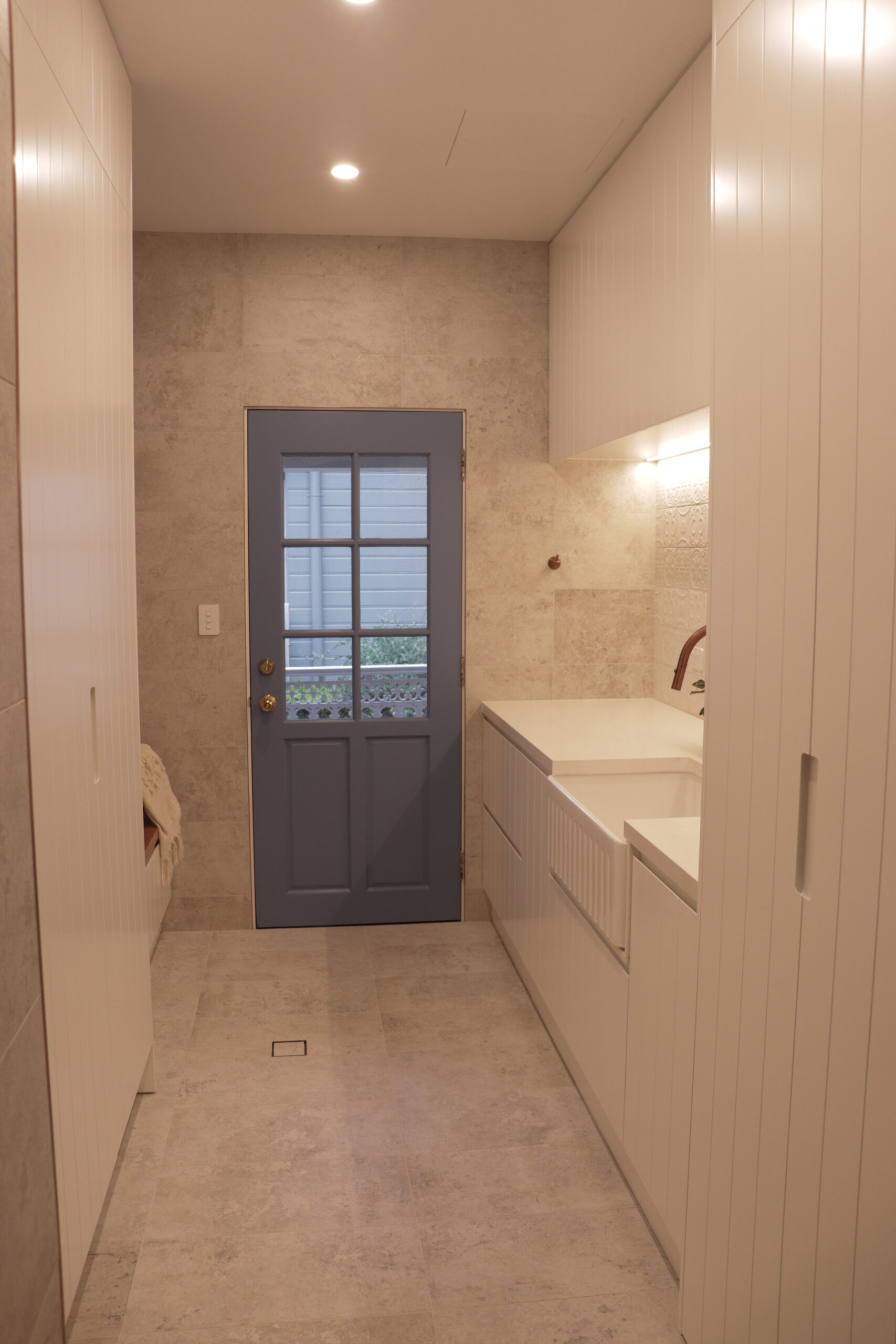 Rustic mudroom entryway with embedded sink on the right, cabinets and blue farmhouse door.